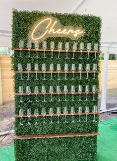 a green wall with wine glasses on it and the word cheers spelled in white letters