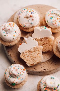 several cupcakes with white frosting and sprinkles on a plate