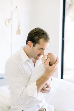 a man sitting on top of a bed holding a baby