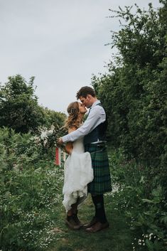 a bride and groom kissing in the woods