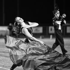 the band is playing on the field with their instruments in hand and one person holding a blue sheet