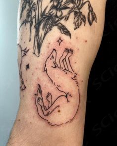 a tattoo on the leg of a man with a wolf and tree in the background