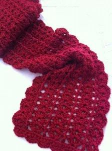 a red crocheted scarf laying on top of a white table