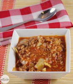 a white bowl filled with soup on top of a red and white checkered table cloth