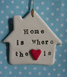 a ceramic house ornament with a red heart hanging from it's side