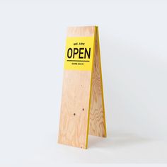 a wooden sign with the words we are open written on it in black and yellow