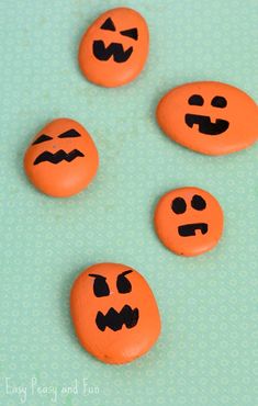 four orange buttons with faces drawn on them sitting on a blue tableclothed surface