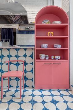 a pink bookcase next to a blue and white tiled wall with circles on it