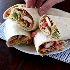 a person is holding a burrito on a plate