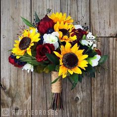 a bouquet of sunflowers, roses and other flowers is tied to a piece of wood