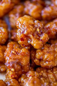 closeup of sweet and sour chicken on a plate with chopsticks in the foreground