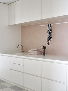 a white kitchen with pink tiles on the wall and cabinets above it is also a sink