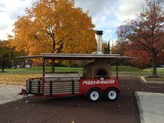 a small pizza cart is parked on the side of the road in front of some trees