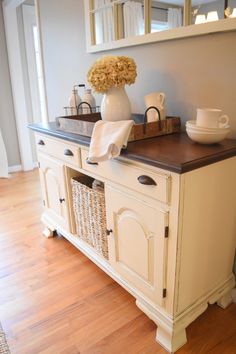 a white cabinet with drawers and baskets on top in a room that has hardwood floors