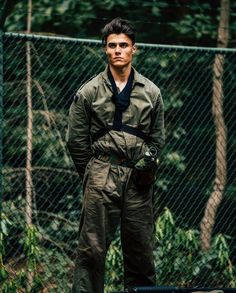 a man standing in front of a chain link fence with his hands on his hips