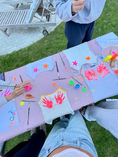 two people sitting at a table covered in handprints and crafting supplies on it