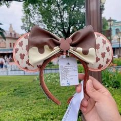 a person holding up a minnie mouse ears headband with a tag attached to it