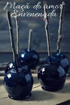 three blue apples sitting on top of a table with sticks sticking out of the tops