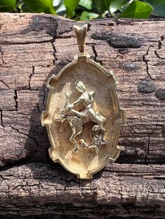 a gold pendant with an image of a man riding a horse on the back of it