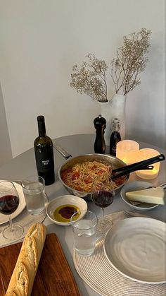 the table is set with bread, wine and pasta