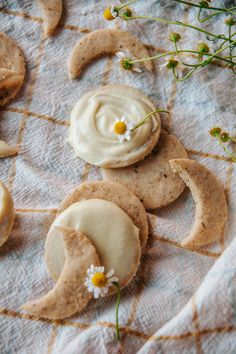 some cookies with icing and flowers on top of a cloth covered in white frosting