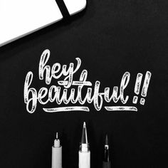 the words hey beautiful are written on a blackboard with markers and pens next to it