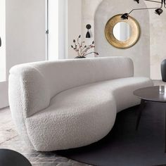 a living room with a white couch and round mirror on the wall next to it