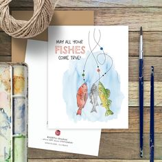 a card with two fish on it next to some watercolors