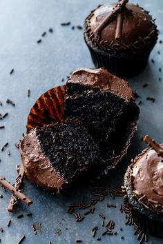 chocolate cupcakes with frosting and sprinkles on a blue surface