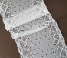 three pieces of white lace sitting on top of a table