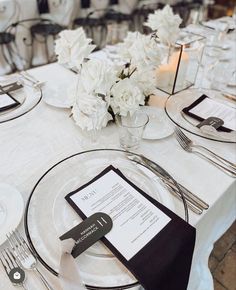 the table is set with white flowers and silverware