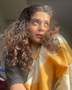 a woman with curly hair is wearing a yellow and white scarf