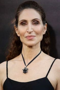 a woman wearing a black dress with a necklace on it's neck and her eyes closed