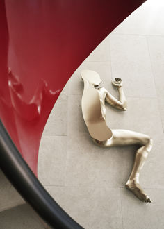 a statue is laying on the floor next to a round table with a red chair