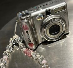 a silver camera sitting on top of a metal table next to a glass beaded chain