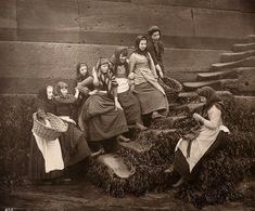 an old black and white photo of women sitting on steps