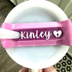 a pink and white toothbrush holder with the word kinley written on it in cursive writing