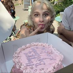 a woman sticking her tongue out in front of a pink cake with the words happy birthday written on it