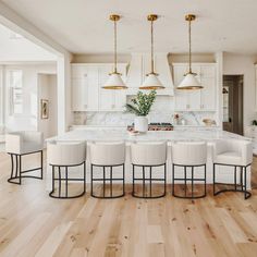 a large kitchen with white cabinets and chairs around the center island in front of an open floor plan