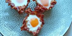 bacon and eggs are arranged in the shape of hearts on a blue plate with black speckles