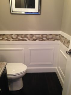 a white toilet sitting in a bathroom next to a mirror on the side of a wall