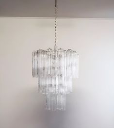 a chandelier hanging from the ceiling in a room with white walls and flooring