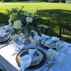 a table set with plates, silverware and flowers in a vase on the table