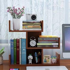 a desk with a computer, books, and other items on it next to a window