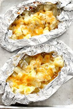 two foil packets filled with food sitting on top of a pan