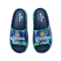 Indulge in laid-back, summer style with these men's blue Corona slide sandals. Immerse yourself in the ultimate relaxation experience as you slip into these comfortable slides, carefully designed to fit men's sizes 7.5-12. The iconic beer logo, surrounded by lush palm leaves, adorns the straps, creating a custom design that embodies the essence of leisure. Crafted from high-quality EVA materials, these officially licensed sandals offer both durability and comfort. Whether you're strolling on the Blue Slip-on Summer Flip Flops, Comfortable Blue Slippers For Vacation, Casual Blue Flip Flops For Summer, Blue Slides For Summer, Blue Non-slip Slides For Vacation, Non-slip Blue Slides For Vacation, Blue Slide Sandals For Outdoor, Blue Casual Outdoor Slippers, Comfortable Blue Beach Slippers