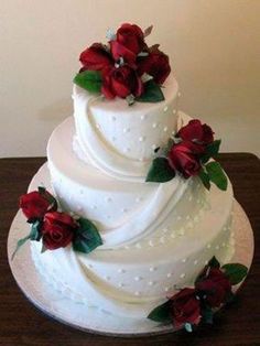 a three tiered white wedding cake with red flowers