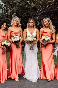 the bride and her bridesmaids are all wearing coral colored dresses with white flowers in their bouquets