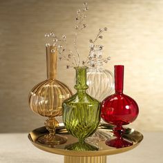 three glass vases sitting on top of a gold plate