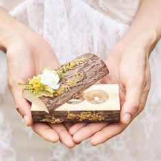 a person holding a piece of wood with flowers in it's hands while wearing a wedding dress